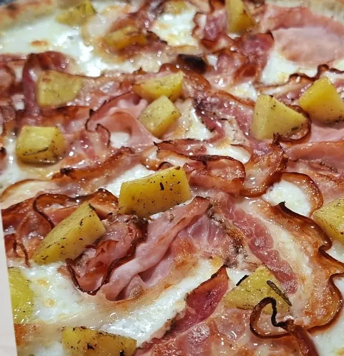 Primo piano della Botero: porchetta e patate al forno sulla mozzarella filante