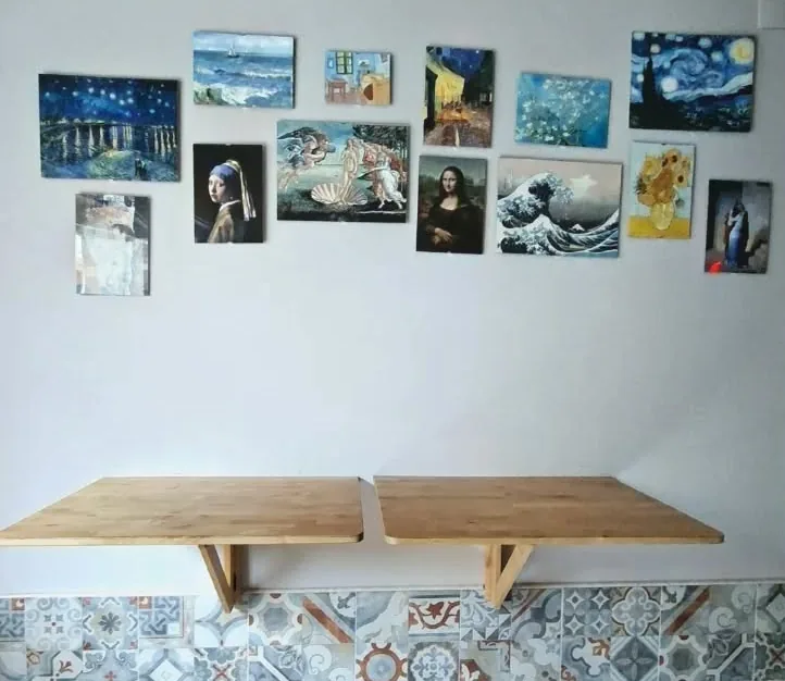 Una parete del locale: le riproduzioni di Van Gogh, Vermeer, Botticelli, Leonardo e Hokusai sopra i piani in legno e le maioliche